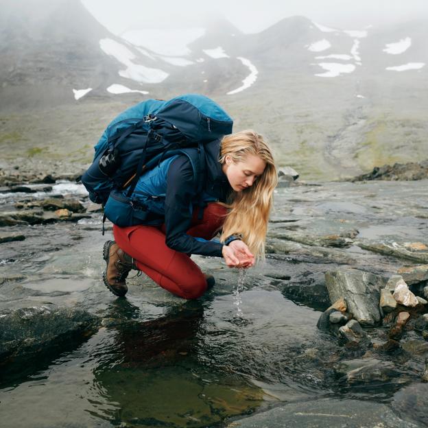 Hiker collecting water from mountain stream