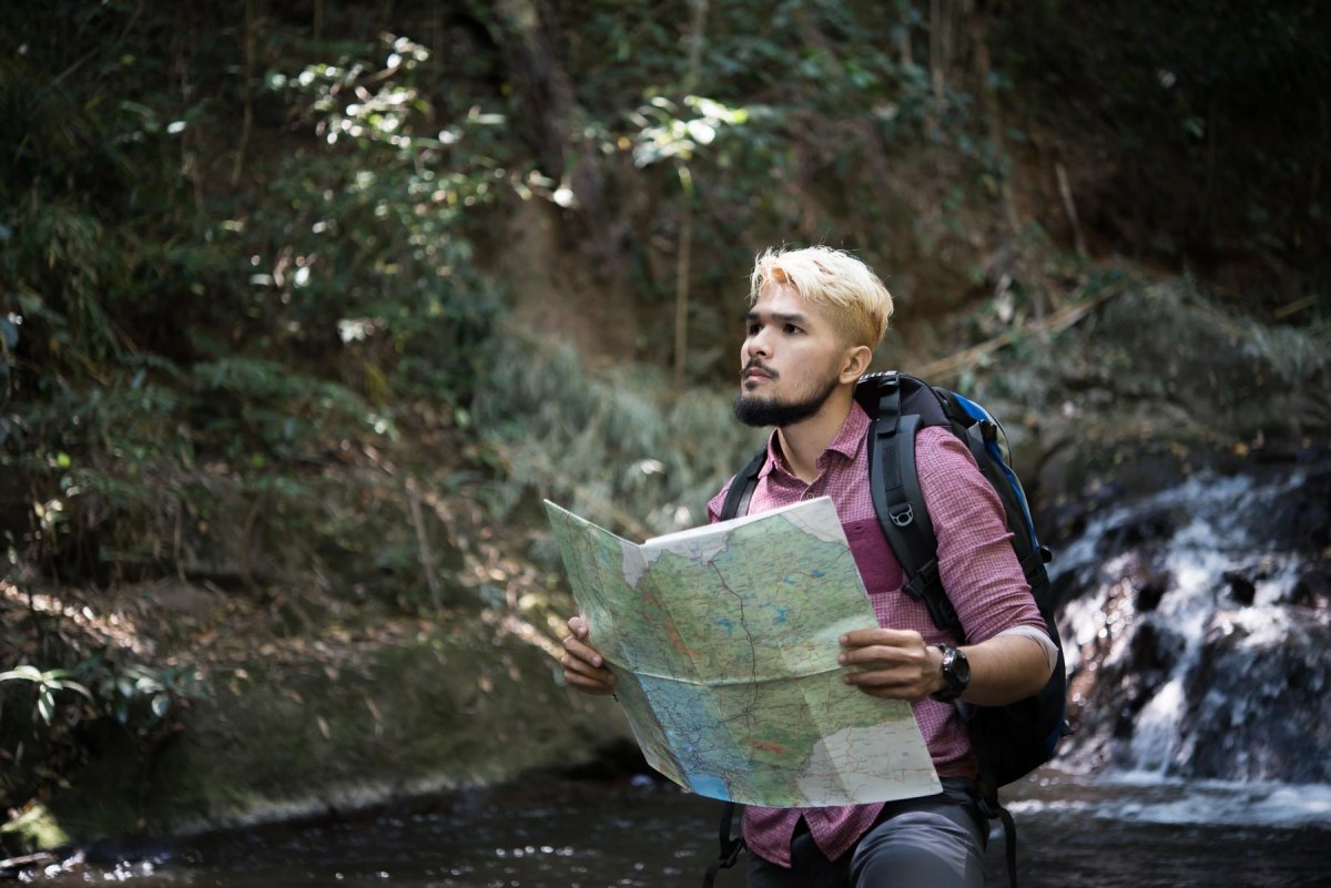 Backpacker planning trail water stops with map